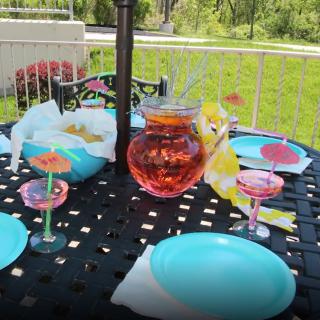 A colorful outdoor table setup with blue plates and refreshing drinks in a garden setting.