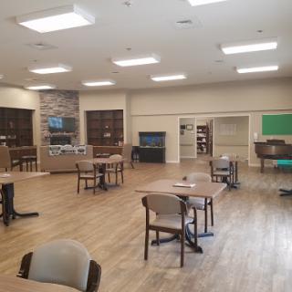 A spacious and well-lit interior room with tables and chairs arranged for activities.