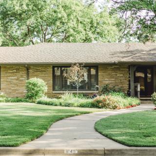 A well-maintained brick house with a neat lawn and garden path.