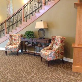 A cozy seating area with floral chairs and a decorative staircase.
