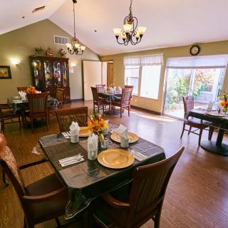 A well-lit dining room with elegantly set tables and chandeliers.