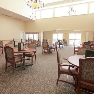 A spacious dining area with multiple tables and chairs, featuring large windows and chandeliers.