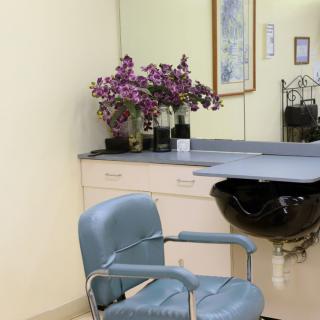 A salon interior featuring a chair, counter with flowers, and a mirror.