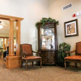 A cozy living room area featuring two chairs, a decorative cabinet, and artwork on the wall.