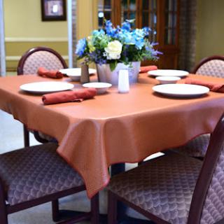 A beautifully arranged dining table featuring an orange tablecloth, elegant plates, and a floral centerpiece.