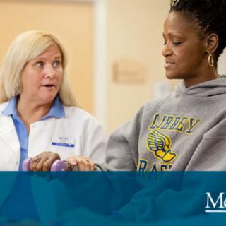 A healthcare professional assists a patient during a physical therapy session.