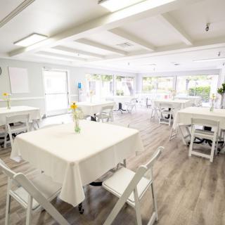 A bright and airy dining area with white tables and chairs.
