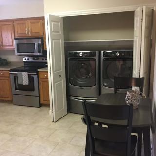 A modern kitchen with stainless steel appliances and a laundry area.