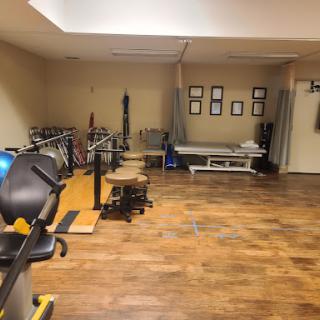 A well-equipped gym space featuring various exercise equipment and a clean wooden floor.