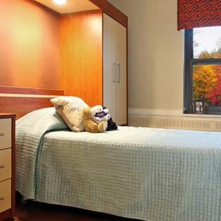 A cozy bedroom with a neatly made bed and a teddy bear.