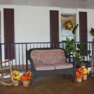 A cozy porch scene with a cushioned bench, rocking chair, and autumn decorations.