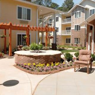 A beautifully landscaped courtyard with a pergola and outdoor seating in an apartment complex.