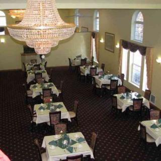 An elegant dining room with neatly arranged tables and a large chandelier.
