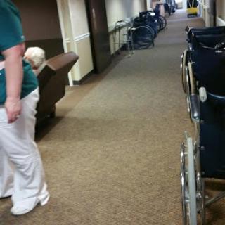 A healthcare worker attending to residents in a hallway equipped with wheelchairs.