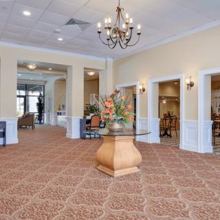 A spacious and elegantly decorated lobby featuring a chandelier and a table with a flower arrangement.