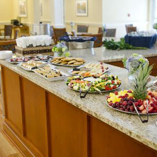 A buffet table with an assortment of food, including sandwiches, cookies, and fruit platters.