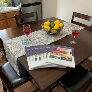 A cozy dining table setting with cookbooks, glasses of wine, and a bowl of lemons.