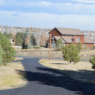 A peaceful countryside scene with a wooden house, surrounded by trees and a winding pathway.