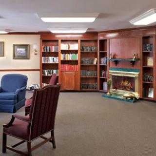 A cozy library interior with bookshelves, armchairs, and a fireplace.