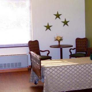 A cozy room with a bed, two chairs, a small round table, and star-shaped wall decorations.