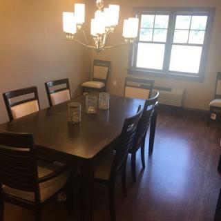 A dining room with a large table, several chairs, and a chandelier.