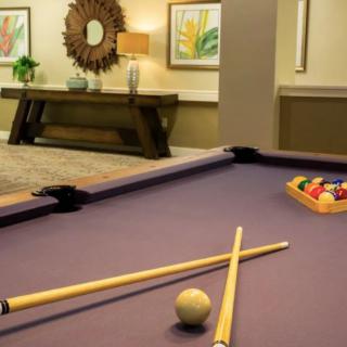 A stylish game room featuring a pool table with cue sticks and billiard balls, ready for play.