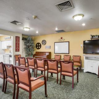 A cozy meeting room with rows of chairs facing a television and whiteboard, set up for a lecture or presentation.