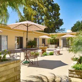 A sunny courtyard with outdoor seating, umbrellas, and lush greenery.