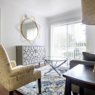 A cozy living room with a patterned rug, modern furniture, and large windows allowing natural light.