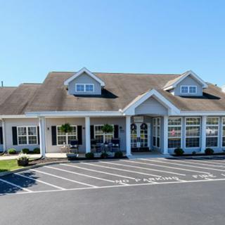 A suburban-style office building with a parking lot in front, featuring large windows and a central entrance.