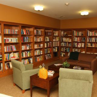 A cozy library reading area with bookshelves, chairs, and a couch.
