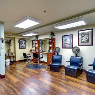 A cozy salon interior with styling stations, comfortable chairs, and hair dryers.