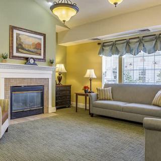 A cozy living room with a fireplace, sofas, and large windows.