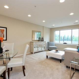 A modern living room with a seating area, dining table, and large window.