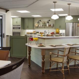 A modern kitchen with green cabinetry, an island counter, and stylish pendant lighting.