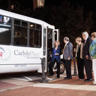 A group of people boarding a bus at night in an urban area.