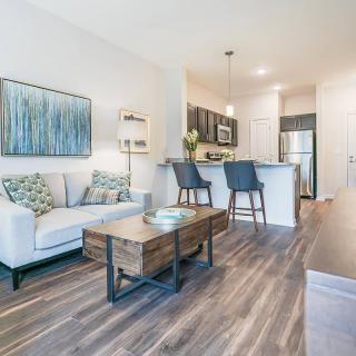 A modern open-layout living room and kitchen with stylish furniture and wood flooring.