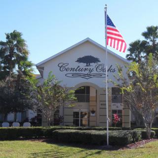 A building with an American flag in front, surrounded by palm trees.