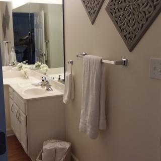 A neatly organized bathroom with a sink, mirror, and towels.