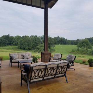 A cozy outdoor patio with comfortable seating overlooking a lush green landscape.