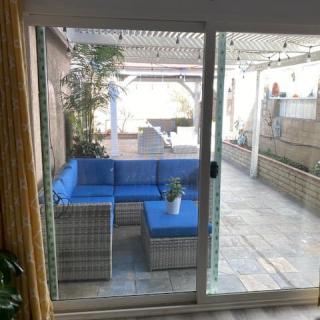 A cozy outdoor patio with blue cushioned seating and a glass sliding door.