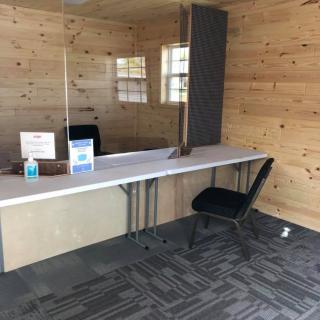 A small office reception area with a wooden interior and protective partition.