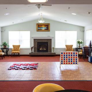 A spacious living room with a fireplace, large windows, and games like Connect Four set up on the floor.
