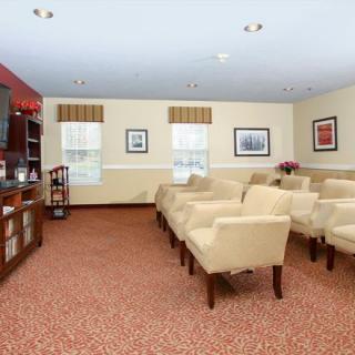 A well-arranged room featuring rows of beige chairs facing a television with framed art on the walls.