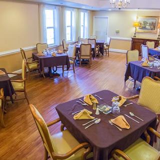 A neatly arranged dining room with multiple tables and chairs, set for a formal meal.