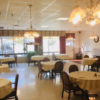 A well-lit dining area with round tables and elegant chandeliers.