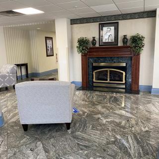 A cozy lobby area featuring a fireplace, armchair, and decorative plants.