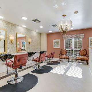 An elegant hair salon interior with stylish chairs and well-lit mirrors.