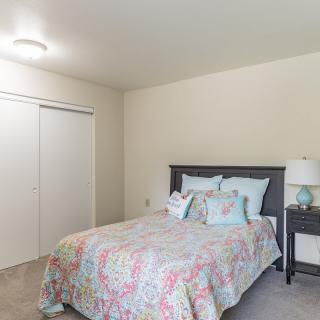 A cozy bedroom with a colorful bedspread and a nightstand lamp.