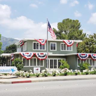 A beautifully decorated building with patriotic bunting and an American flag, set against a clear sky.
